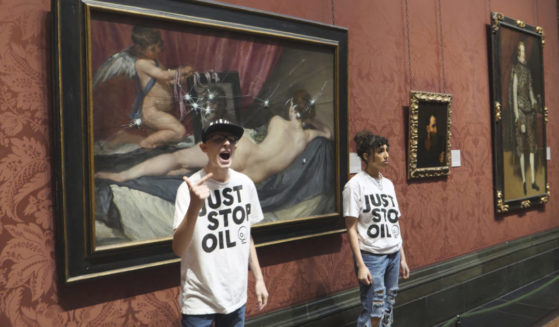 In this photo provided by Just Stop Oil on Monday, climate activists stand by a painting after smashing its protective panel at the National Portrait Gallery in London.