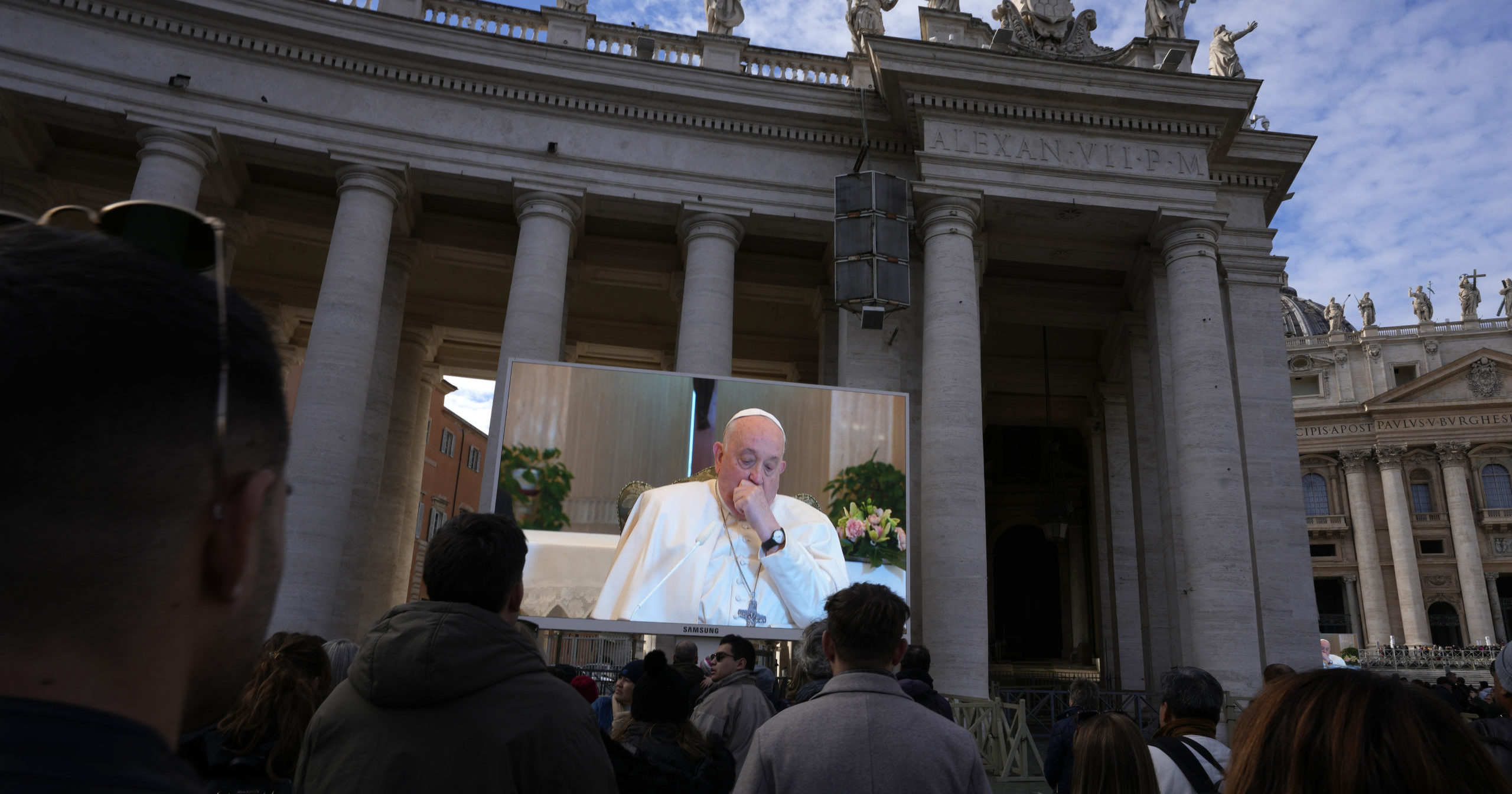 A giant screen broadcasts Pope Francis coughing during the Angelus noon prayer, from the chapel of the hotel at the Vatican grounds where he lives, on Sunday.