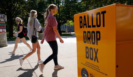 University of Illinois students walk past a mail-in ballot drop box at the campus in Urbana on Oct. 6, 2020.