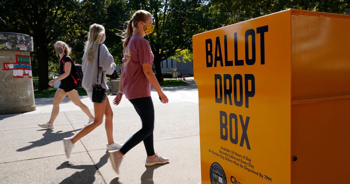 University of Illinois students walk past a mail-in ballot drop box at the campus in Urbana on Oct. 6, 2020.