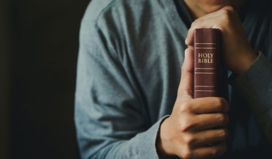 A man holds a Bible in this stock image.