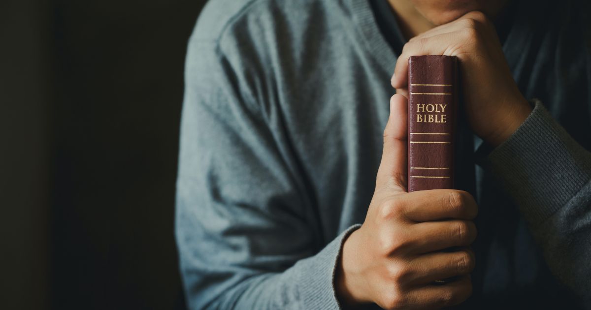 A man holds a Bible in this stock image.
