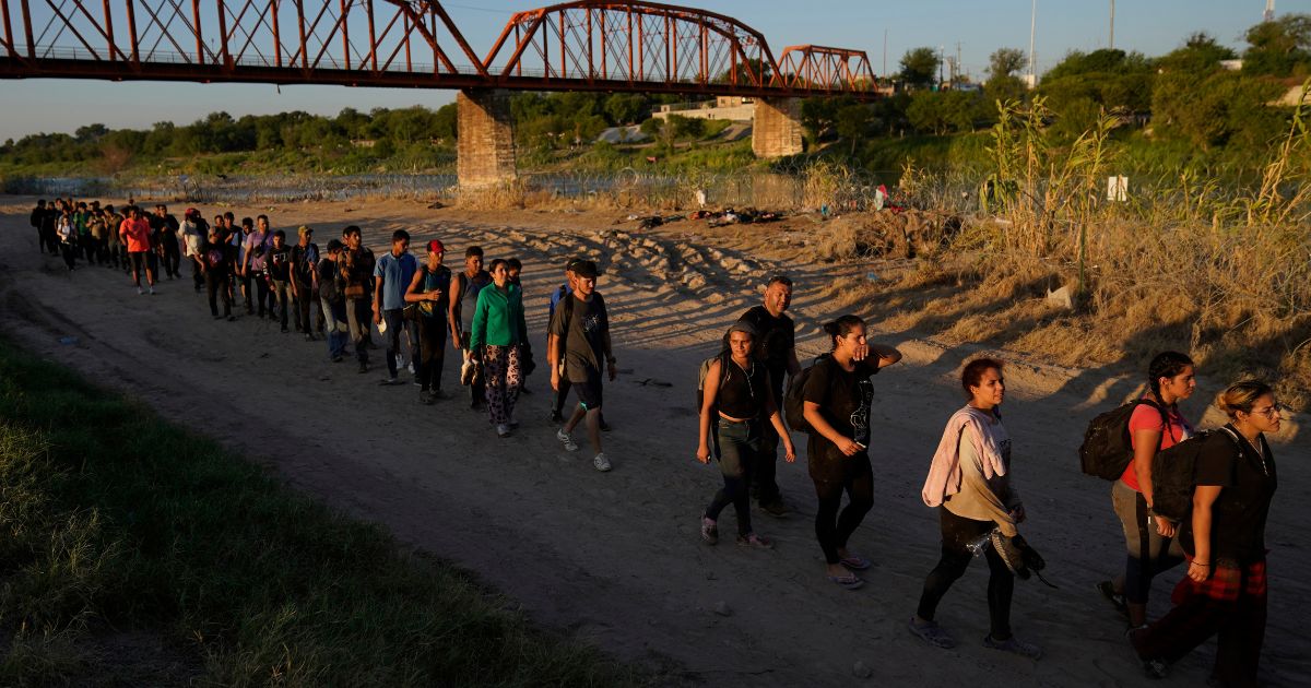 Migrants who crossed the Rio Grande and entered the U.S. from Mexico are lined up for processing by U.S. Customs and Border Protection on Sept. 23 in Eagle Pass, Texas.