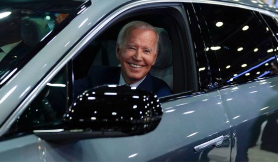 Joe Biden not looking where he's going as he drives a Cadillac Lyriq through a showroom