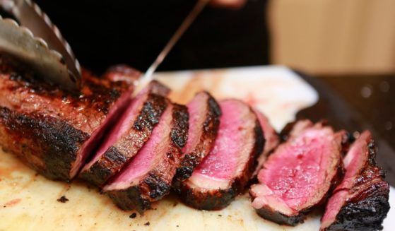 Medium rare beef is being sliced by a cook. According to a report, the UN will seek to tell Americans to cut down on their meat consumption.