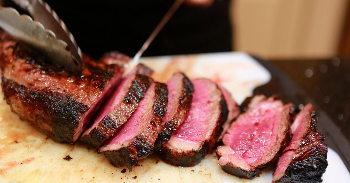 Medium rare beef is being sliced by a cook. According to a report, the UN will seek to tell Americans to cut down on their meat consumption.