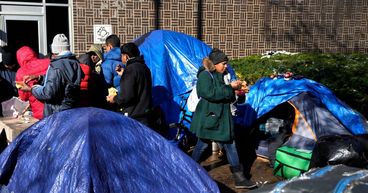 Hot dogs are served to migrants outside a Northside police station in Chicago where they live in a tent community on Nov. 1.