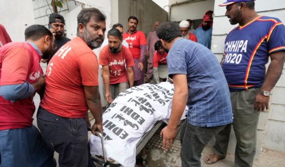 Men carry a body in Karachi, Pakistan, Saturday. At least 10 people were killed and 22 injured in the blaze at RJ Mall on Rashid Minhas Road in Karachi.
