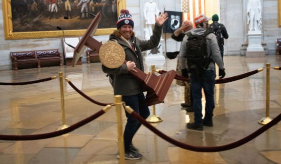 A protester identified as Adam Johnson carries the lectern of House Speaker Nancy Pelosi through the Rotunda of the U.S. Capitol Building on Jan. 6, 2021.