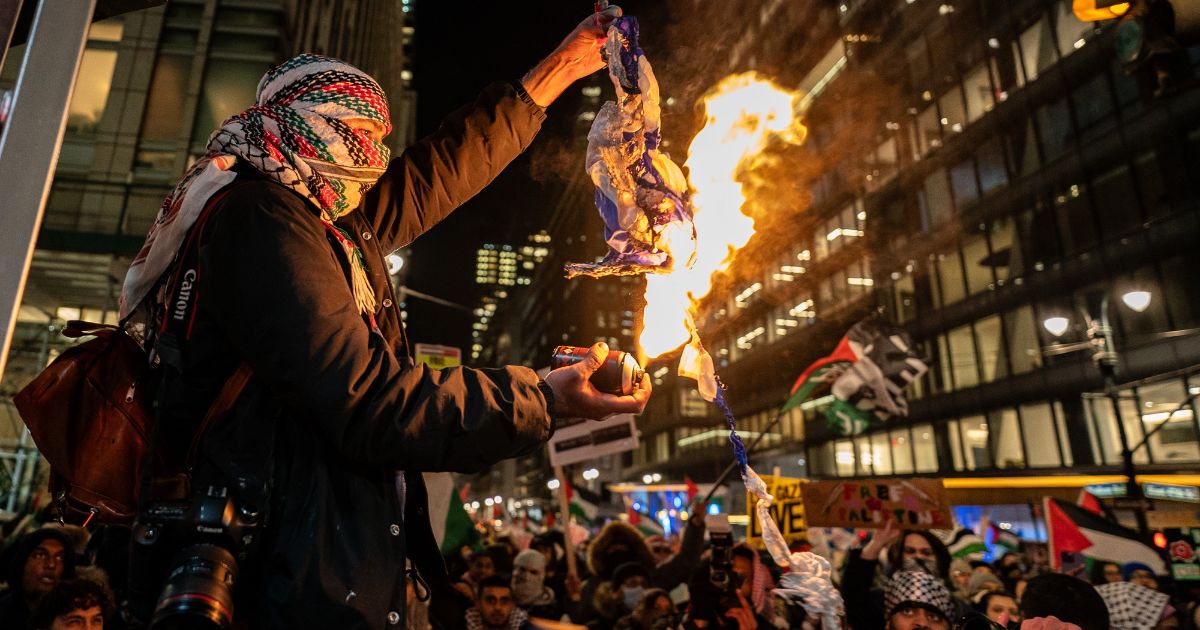 A pro-Palestinian protester burns an Israeli flag during a protest that turned violent during the lighting of the Christmas tree at Rockerfeller Center in New York City on Wednesday.