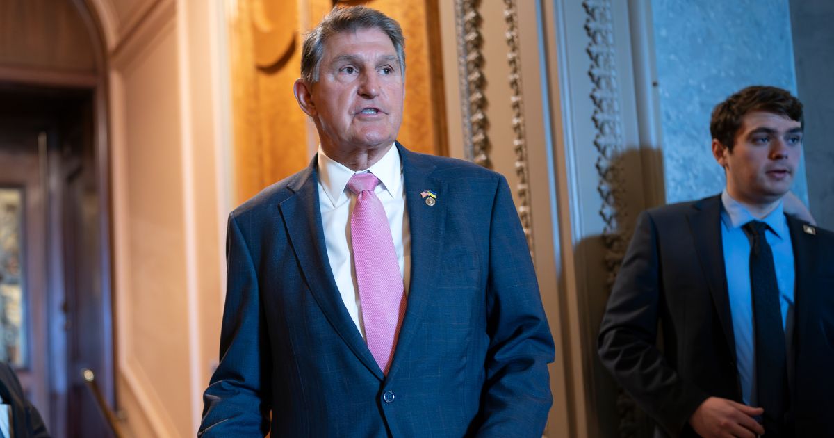 Joe Manchin speaking to a colleague just outside the Senate chamber