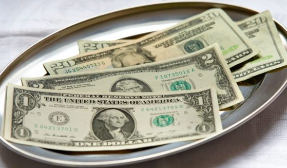 several U.S. bills lying together on a silver platter