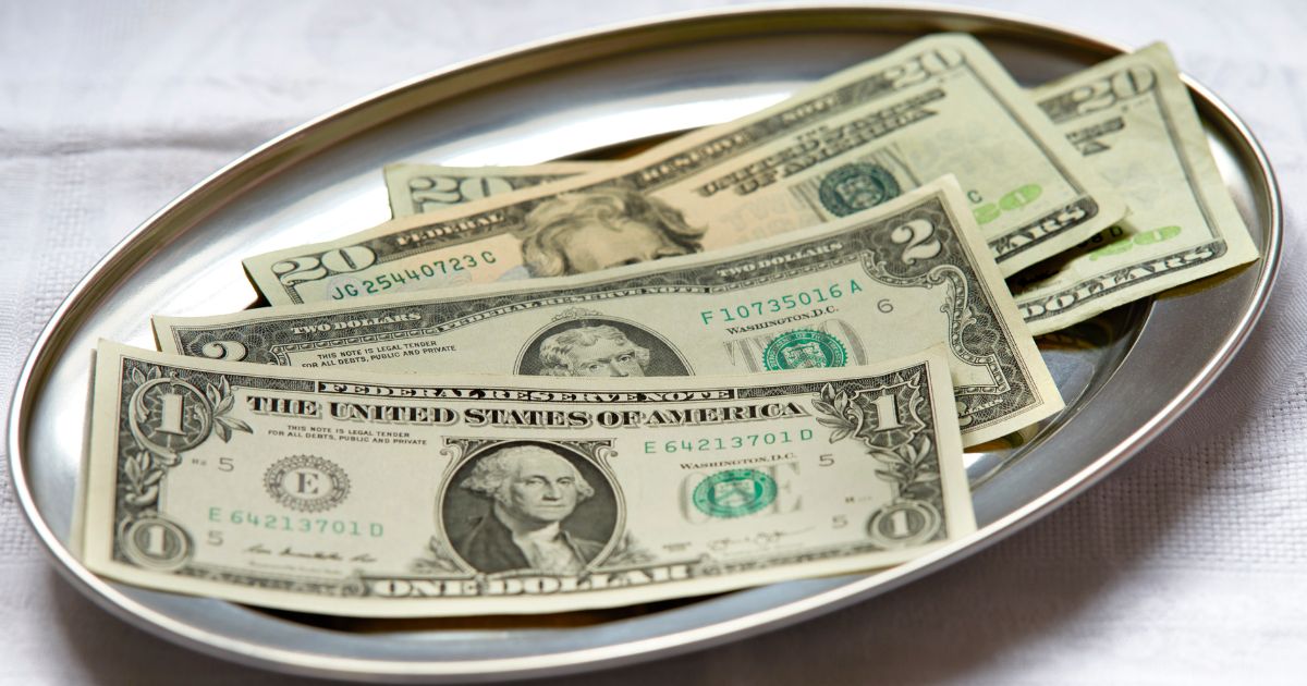 several U.S. bills lying together on a silver platter