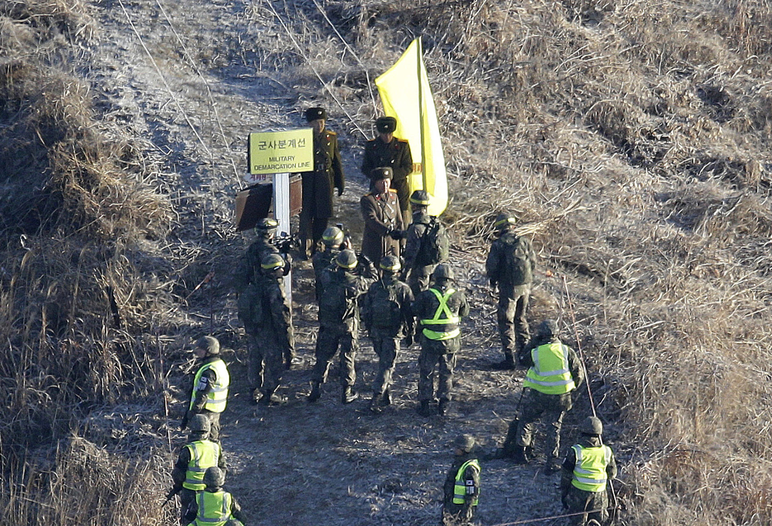 A South Korean army solider, center bottom, shakes hands with a North Korean army soldier, center top, before crossing the Military Demarcation Line inside the Demilitarized Zone to inspect a dismantled North Korean guard post in the central section of the inter-Korean border in Cheorwon on Dec. 12, 2018.