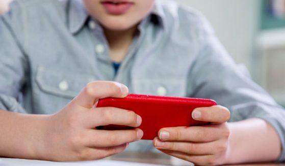 This stock photo shows a young boy playing games on his smart phone.