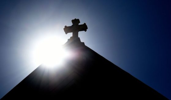 The sun rises behind a stone cross atop the historic Cathedral Basilica of St. Frances of Assisi in Santa Fe, New Mexico.