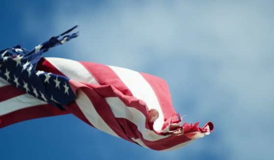 A tattered American flag flies in this stock image.