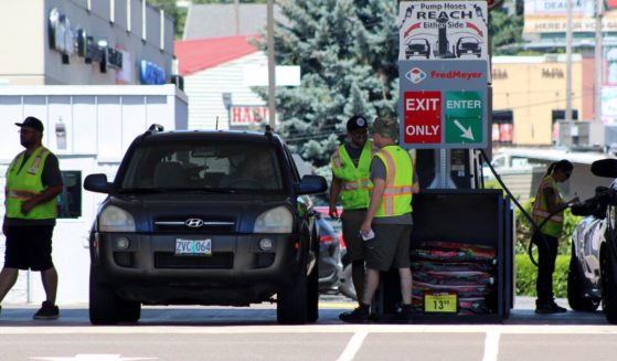 Attendants in vests service cars at a gas station in Salem, Oregon, on June 22.