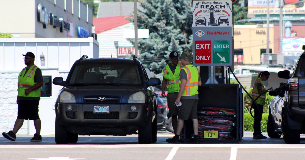 Attendants in vests service cars at a gas station in Salem, Oregon, on June 22.