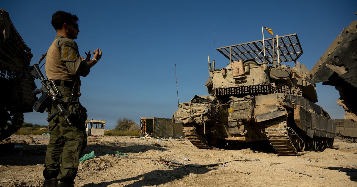 An IDF soldier directs a tank driver by gesturing near the northern Gaza border on November 17, 2023 in Southern Israel.