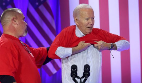 President Joe Biden puts on a United Auto Workers (UAW) shirt before speaking to autoworkers at the Community Complex Building on November 9, 2023 in Belvidere, Illinois.