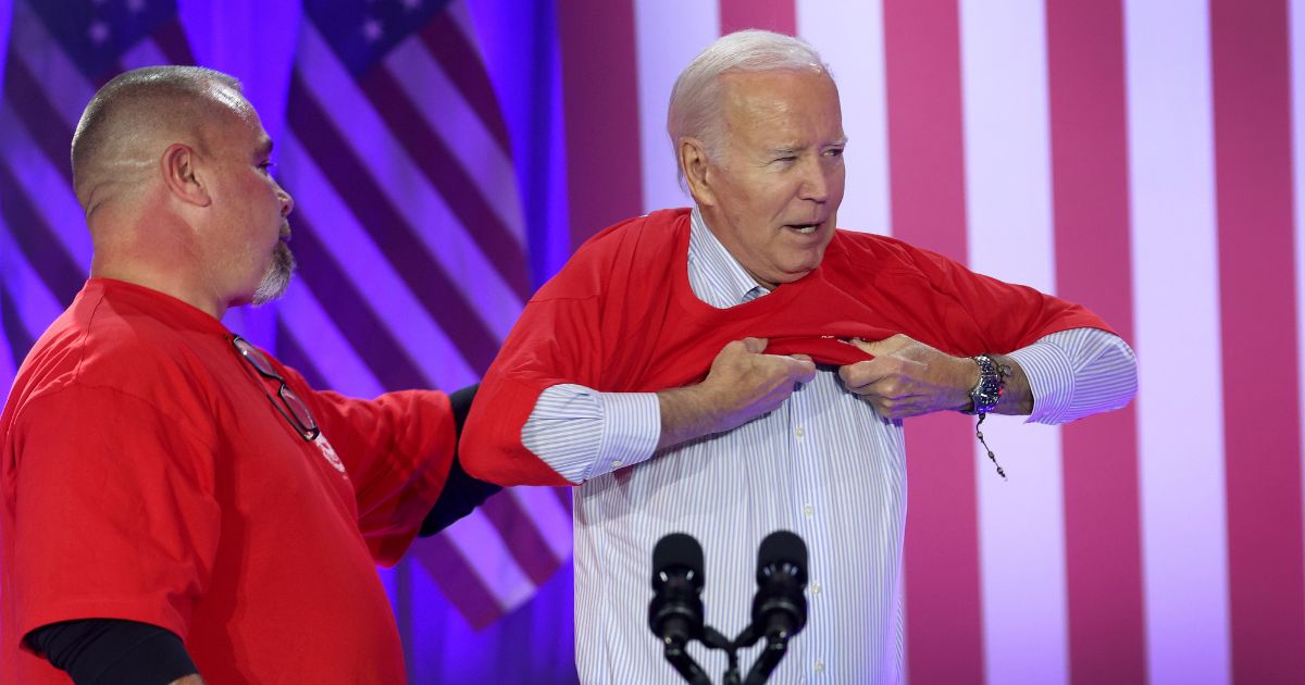 President Joe Biden puts on a United Auto Workers (UAW) shirt before speaking to autoworkers at the Community Complex Building on November 9, 2023 in Belvidere, Illinois.