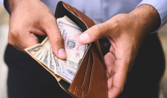 A man opens a wallet in the above stock image.