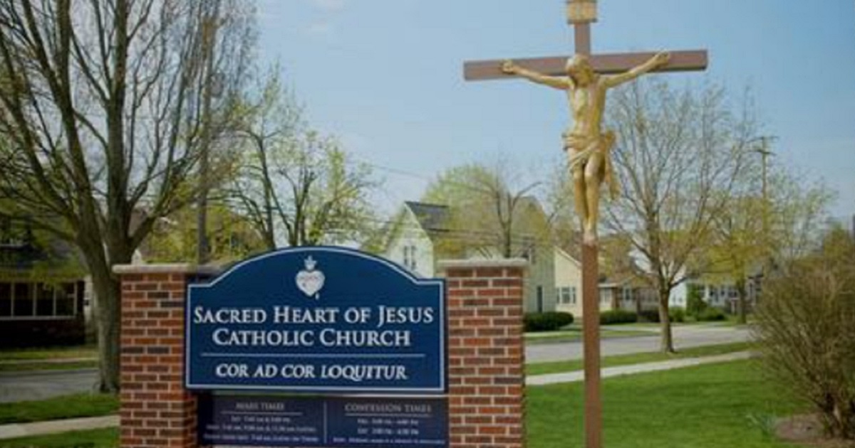 A sign and crucifix outside Sacred Heart of Jesus Parish and school in Grand Rapids, Michigan.