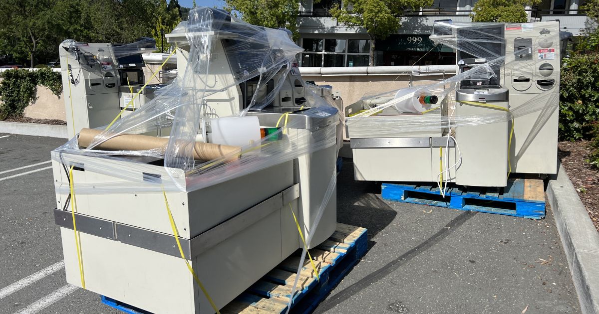 Several self checkout stations are wrapped in shrink wrap in the parking lot of a supermarket in Lafayette, California during self checkout station installation or removal, June, 2023.