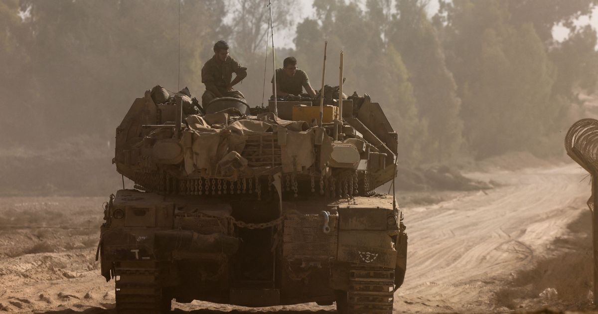 Israeli soldiers sit on the turret of a tank as it rolls along the border with Gaza in southern Israel on Sunday.