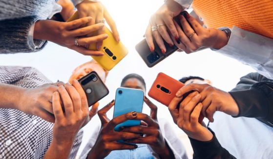 This stock image depicts a number of teenagers using smart phones.