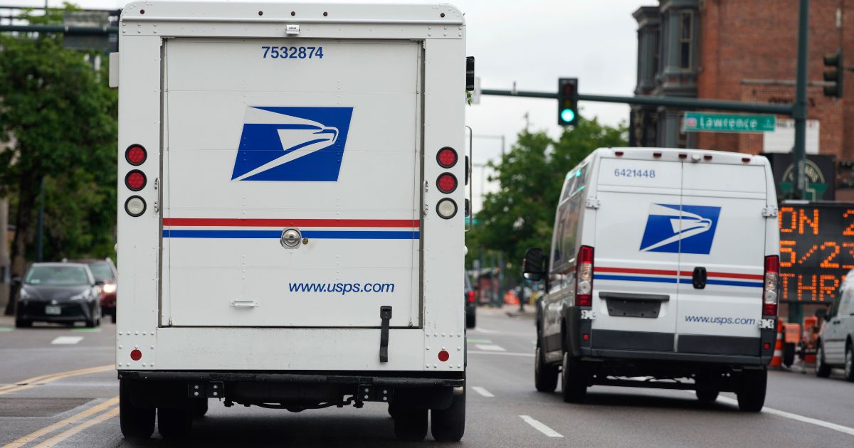 A USPS logo adorns the back doors of United States Postal Service delivery vehicles as they proceed n downtown Denver on June 1, 2022.