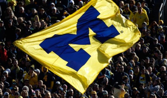 Michigan Wolverine football fans are pictured in a 2016 file photo waving a team flag.