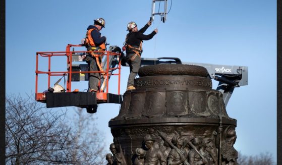 Workers lower a ladder into a monument as they dismantle the Confederate Memorial at Arlington National Cemetery Wednesday in Arlington, Virginia.