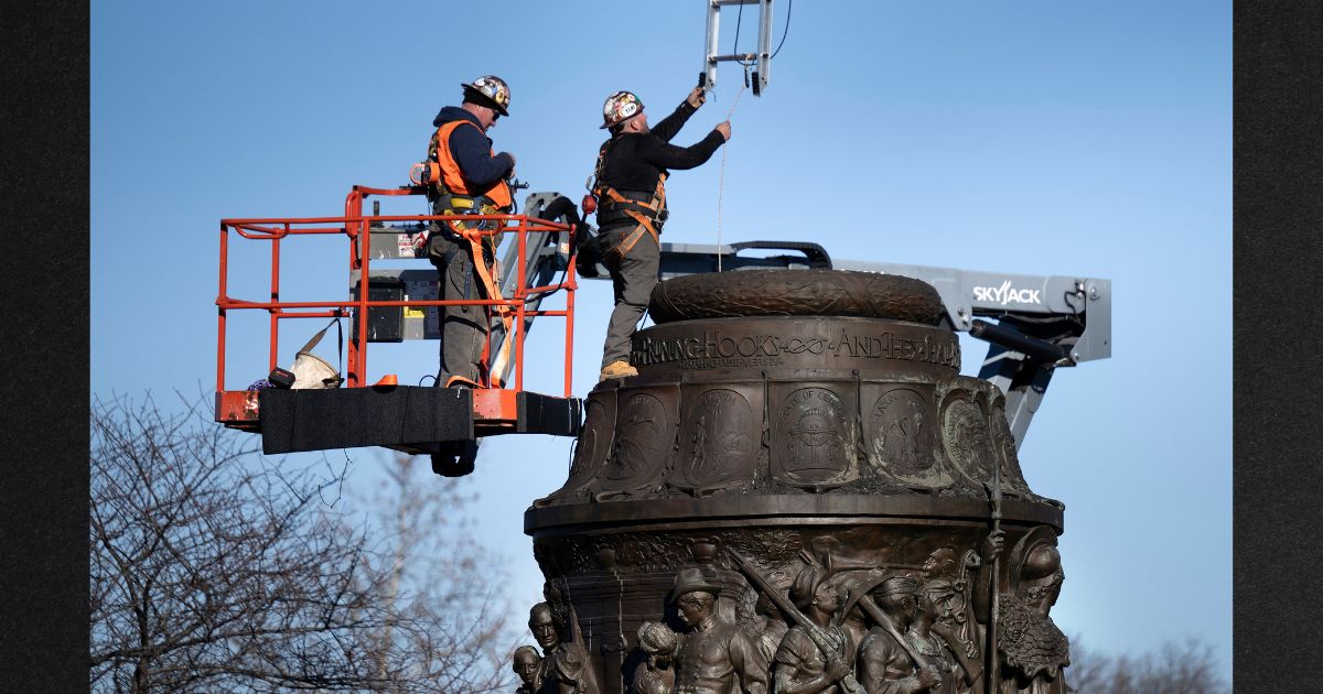 Workers lower a ladder into a monument as they dismantle the Confederate Memorial at Arlington National Cemetery Wednesday in Arlington, Virginia.