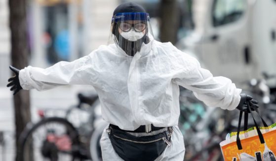 A woman poses wearing a full body hazmat suit, gloves, a protective mask and a face shield while carrying a Trader Joes tote bag amid the coronavirus pandemic in New York City on April 17, 2020.