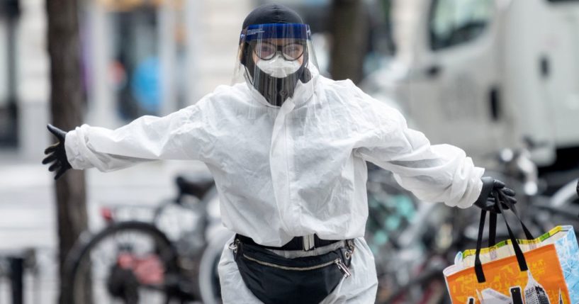 A woman poses wearing a full body hazmat suit, gloves, a protective mask and a face shield while carrying a Trader Joes tote bag amid the coronavirus pandemic in New York City on April 17, 2020.