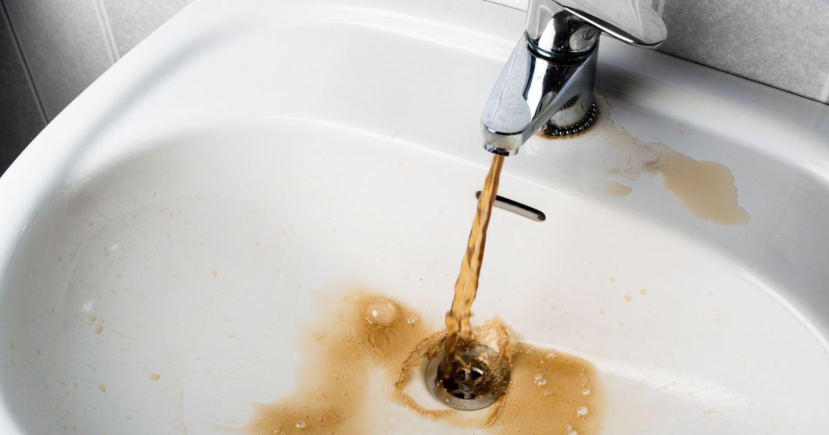 Brown, dirty sink water flows into a sink in this stock photo.