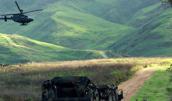 An Army Kiowa helicopter flies over a convoy of U.S. soldiers at the Makua Military Reservation in Hawaii. In a win for Native Hawaiian groups and environmentalists after decades of activism, the U.S. confirmed Friday it will permanently end live-fire training in Makua Valley on Oahu.