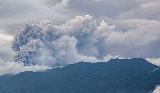 A volcano in western Indonesia erupted on Sunday, belching a column of ash nearly 2 miles into the sky and forcing the evacuation of dozens of hikers, officials said.