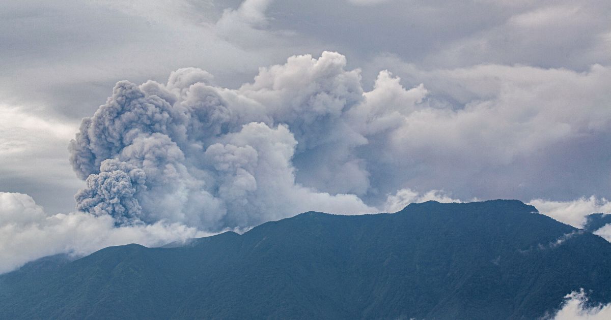 A volcano in western Indonesia erupted on Sunday, belching a column of ash nearly 2 miles into the sky and forcing the evacuation of dozens of hikers, officials said.