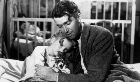Actor Jimmy Stewart, right, hugs actor Karolyn Grime, left, while filming "It's a Wonderful Life."