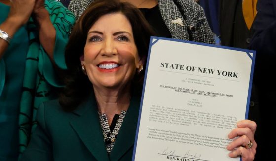 New York Gov. Kathy Hochul holds up signed legislation creating a commission for the study of reparations in New York Tuesday in New York City.