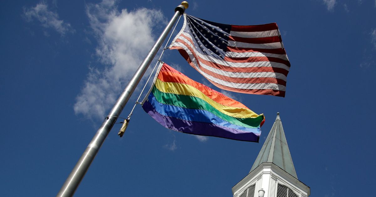 An LGBT "pride" flies with the U.S. flag in front of the Asbury United Methodist Church in Prairie Village, Kansas., on April 19, 2019.
