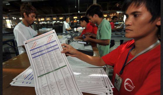 A Smartmatic employee shows a ballot paper after testing it on a election automated machines at the company's warehouse in Cabuyao town, Laguna province south of Manila on May 5, 2010. After 13 years, the Commission on Elections has disqualified Smartmatic Philppines Inc. from participting in its public bidding and procurement processes.