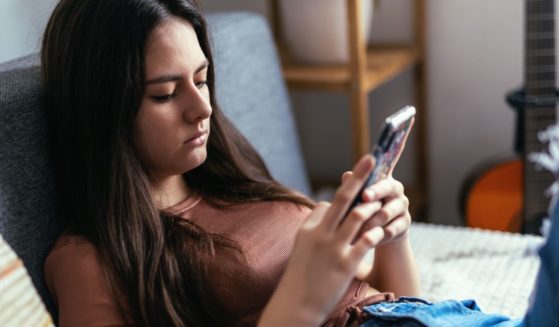 A stock photo shows a teenage girl using social media on a smartphone.