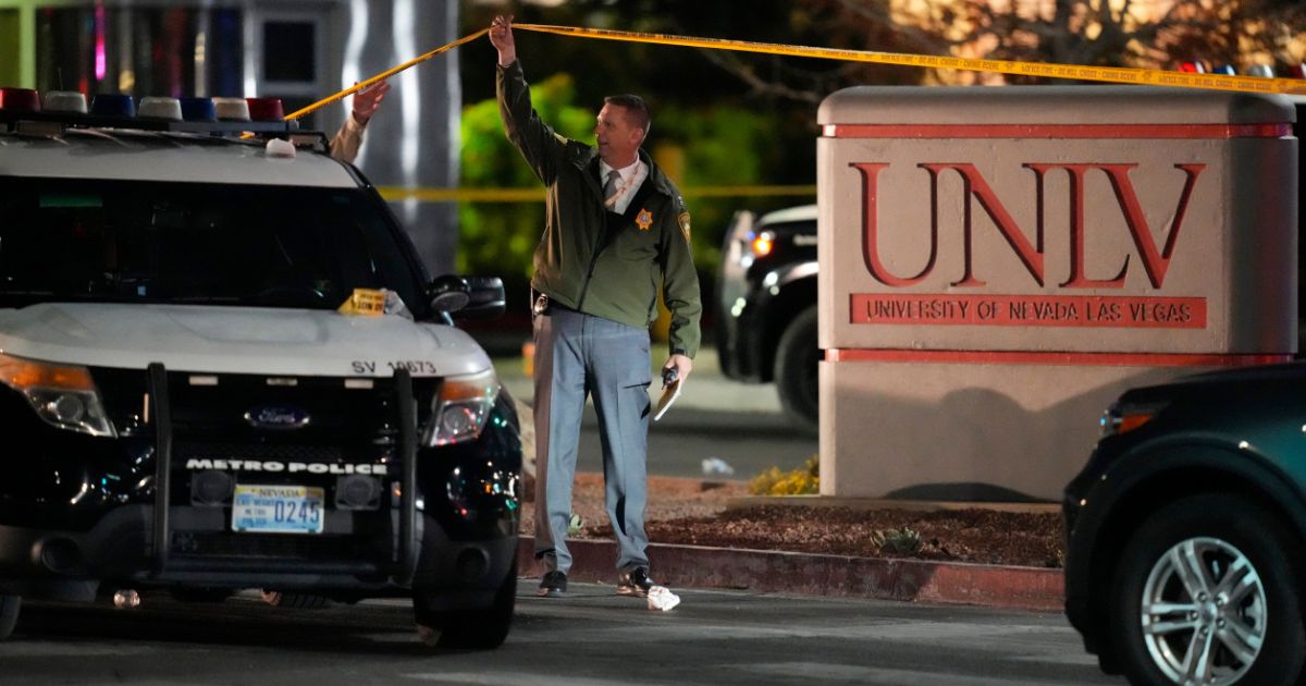 A police officer walks under crime scene tape on the University of Nevada Las Vegas campus following a shooting on the premises on Wednesday.