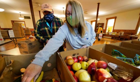 Holly Roberts, right, and Terry Lord pick fruit to be bagged and given away at a food pantry at the First Universalist Church in Norway, Maine, Nov. 25, 2020.
