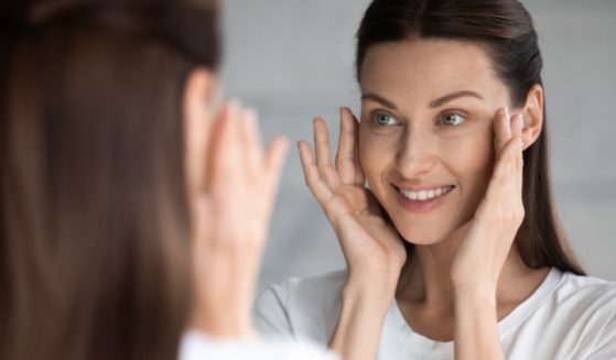 An attractive woman looks in the mirror apparently checking for wrinkles.