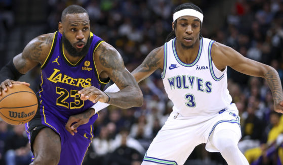 Los Angeles Lakers forward LeBron James, left, works towards the basket as Minnesota Timberwolves forward Jaden McDaniels defends during the second half of an NBA game Saturday, December 30, 2023 in Minneapolis, Minnesota.